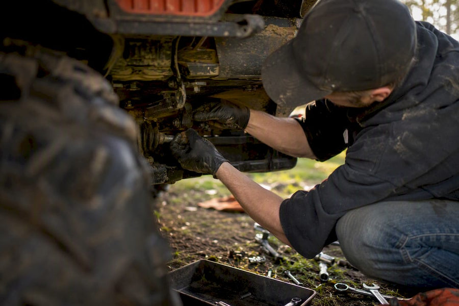 Mechanic hands inspecting partial ATV suspension