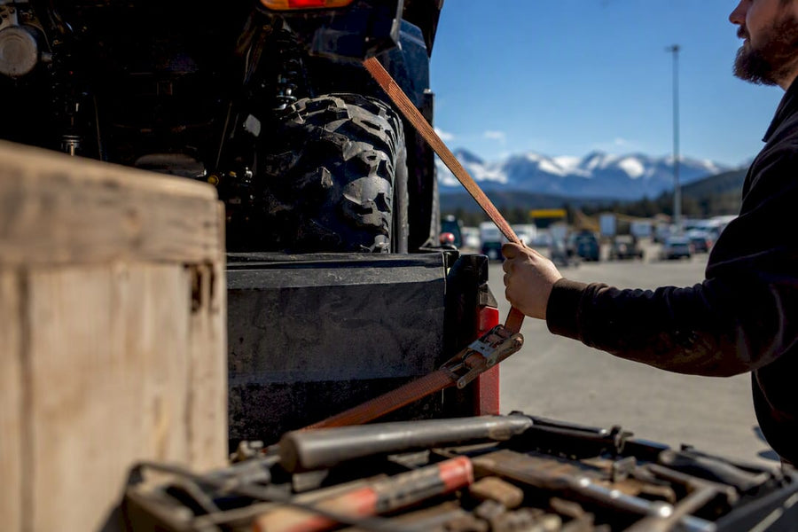 Hand securing ATV with tie-down strap