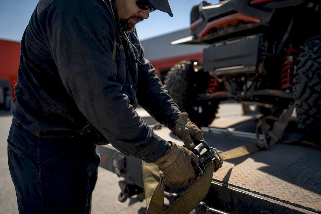 Delivery driver securing straps on powersports freight truck