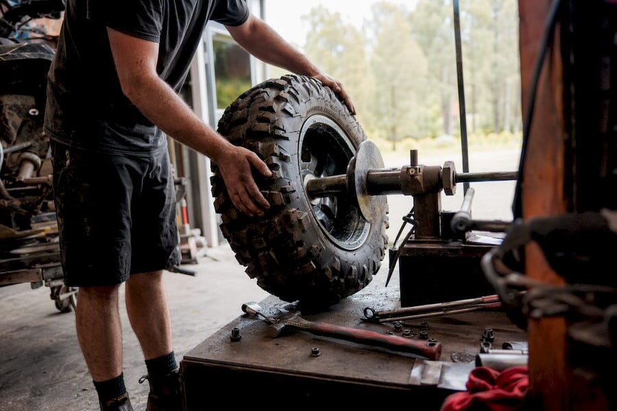 Hands mounting ATV tire at workshop bench