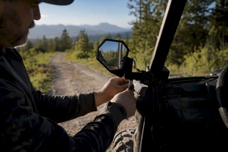 Hands adjusting UTV side mirror outdoors