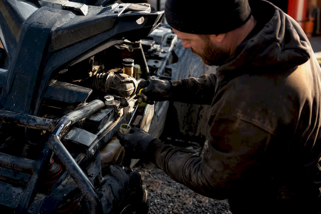 Hands inspecting ATV tire and brakes