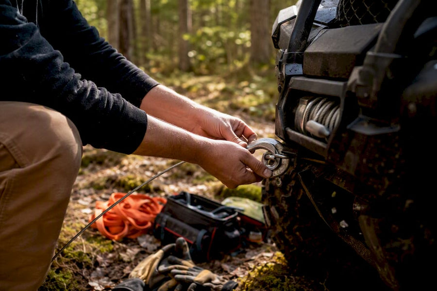 Person attaching winch cable on ATV in forest