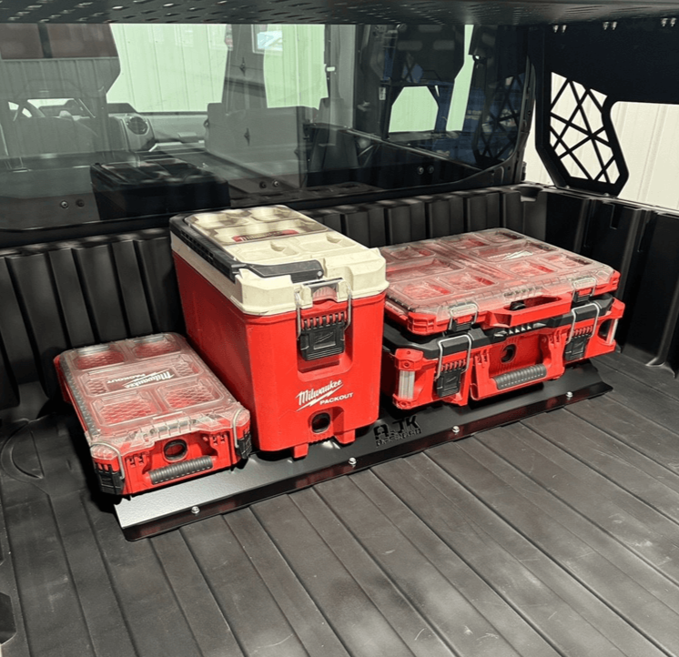 A black metal front packout mount installed in the bed of a Polaris Ranger 1500XD, holding two red and gray tool boxes.